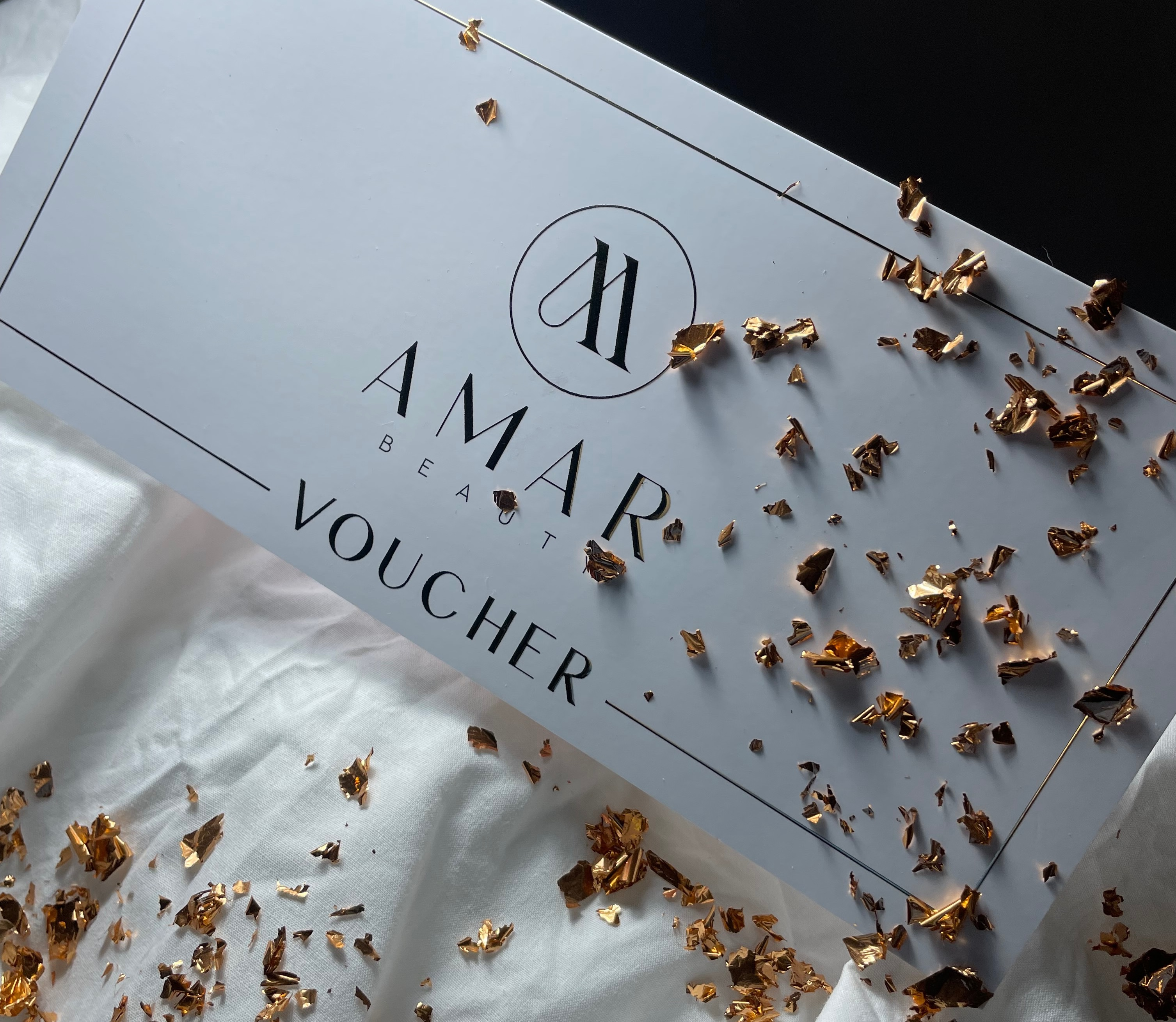 Elegancki voucher prezentowy AMAR Beauty ze złotymi płatkami